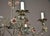 A scrolling wrought iron chandelier with five candle arms, each ending in a leaf-form bobeche and candle sleeve. Painted...