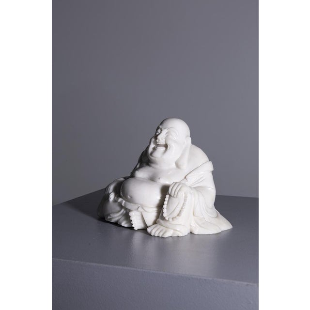 This polished white jade sculpture depicts the Buddha Budai, also known as the Laughing Buddha, in a posture radiating joy...