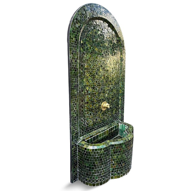 Tall arched traditional mosaic tile wall fountain with Moroccan star patterns. Vibrant jewel-toned emerald coloring. Brass...