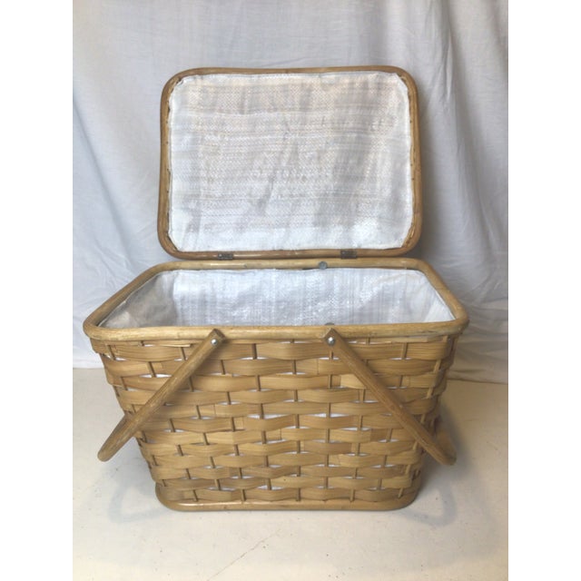 This is a vintage woven basket. This carrying basket features a wide weave with wooden top frame and wooden handles. A...
