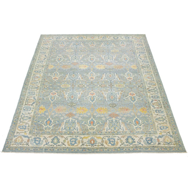 This beautifully crafted hand-knotted oversized Sultanabad wool rug showcases a soothing light blue background embellished...