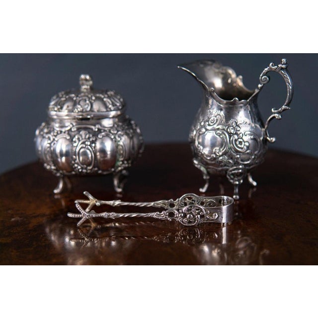 milk jug, sugar bowl, tongs Epoch & style: Baroque style - probably 20th century Features - rich in detail and high...