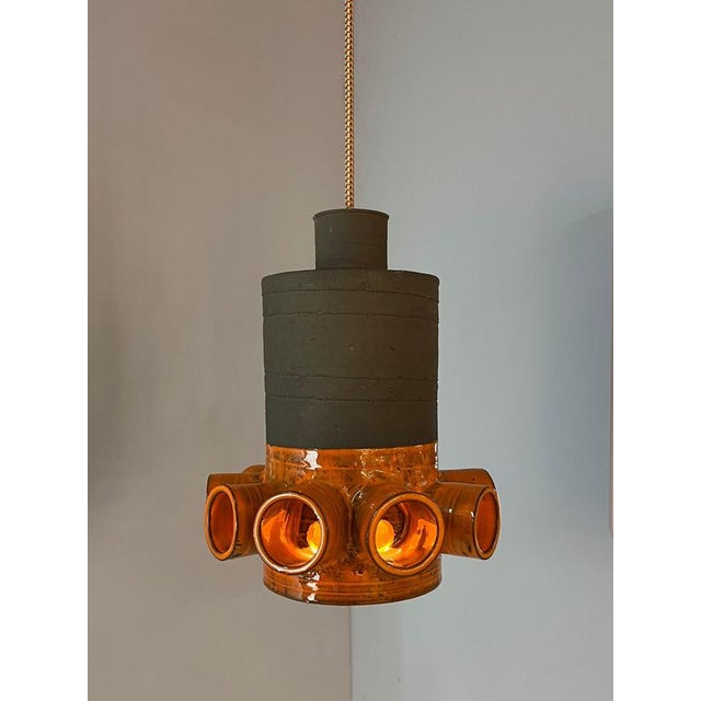 This orange-brown ceramic lamp in the style of West German Pottery combines stylish craftsmanship with a warm color...