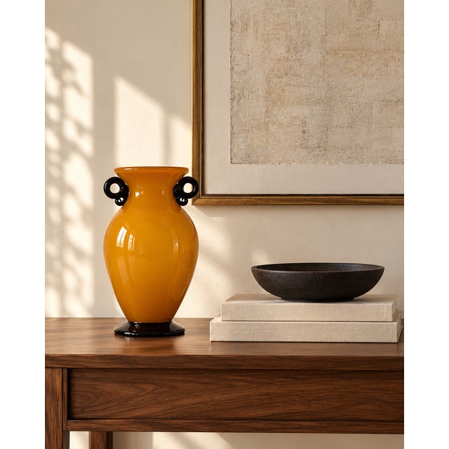 A striking hand-blown art-glass vase featuring a warm ochre-yellow exterior over an opaque white interior. Its full...