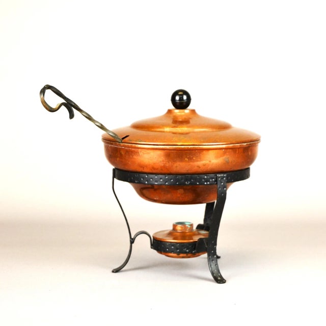A nice copper vessel with a lid on a stand for warming food and a small container for filling with heating oil. The set...