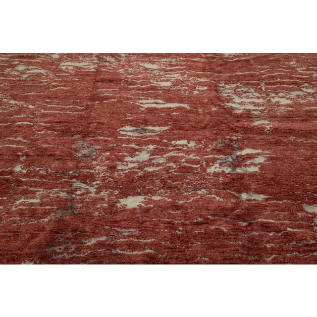 This Indian wool and silk blend rug features a copper field with an abstract pattern detailing beige. Its composed...