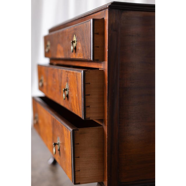 This 1800s vintage walnut dresser features beautifully figured wood grain across its drawer fronts, highlighting the...