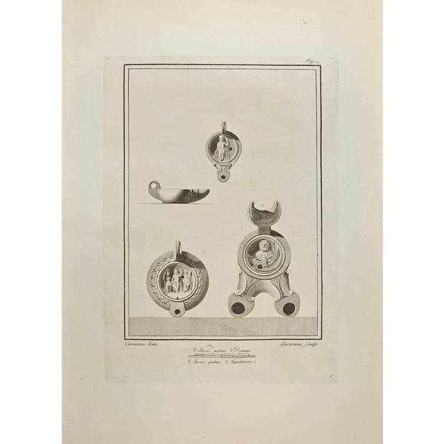 Oil Lamp from "Antiquities of Herculaneum" is an etching on paper realized by Iacomino e Casanova in the 18th Century....