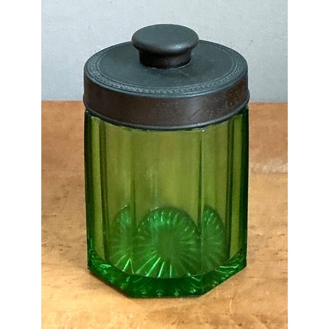 This vintage canister features a striking octagonal glass body in a vibrant emerald green, its eight faceted sides...
