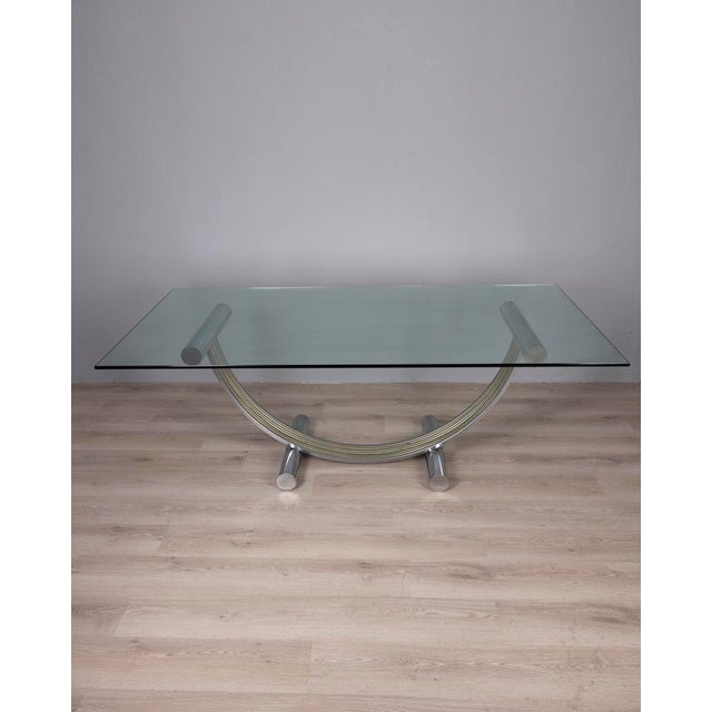 Table with arched base in chromed metal and gilded brass, transparent glass top, designed by Renato Zevi, 1970s. I have...