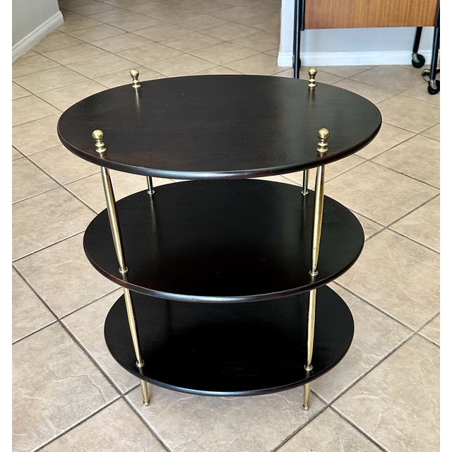 1960's oval English Campaign style 3-tier dark wood side table or etagere, with decorative brass supports and finial...