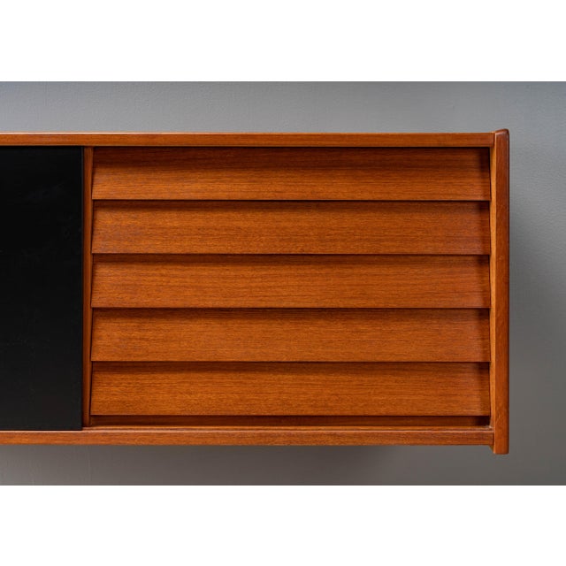Sweden, ca. 1960s. A versatile wall-mounted cabinet by Nils Jonsson for Hugo Troeds. Features teak construction with black...
