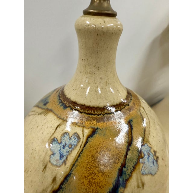 Large bulbous art pottery handcrafted ceramic table lamp. In cream and earth colors with blue flowers.