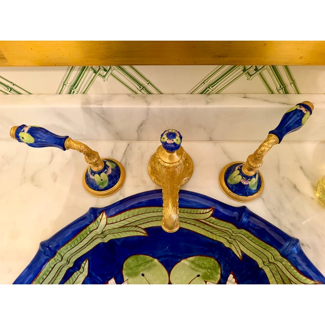 The Sherle Wagner Lotus Blossom Sink features a vibrant blue ceramic basin with intricate hand-painted lily pad and...