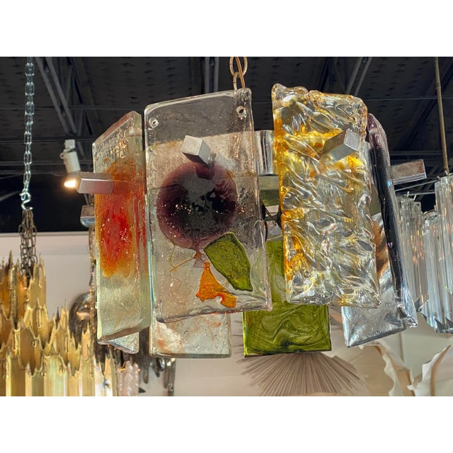 Magical vintage Murano Mazzega colorful glass chandelier. Holds 3 lightbulbs. Has 8 glass pieces with assorted designs and...