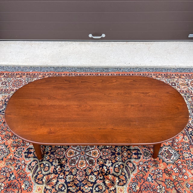 A vintage American Shaker style solid cherry coffee table having an oval shaped top and splayed square tapering legs....