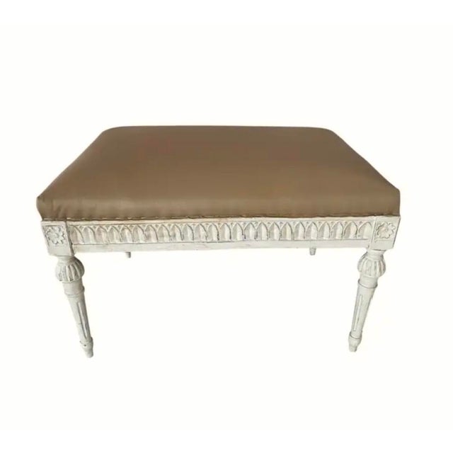 Antique Gustavian Style Hand-Carved Upholstered Stool. Stool features a neutral tan-colored top with painted and carved...