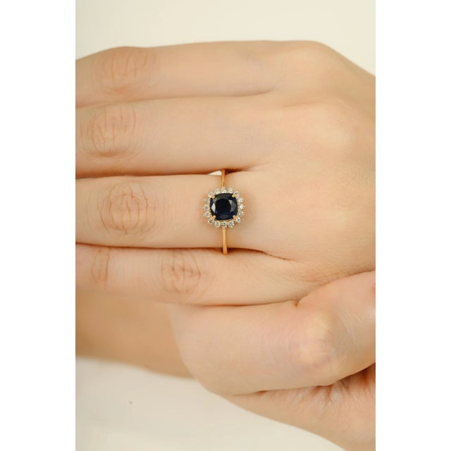 This vintage-style ring features a 1.00 ct cushion cut natural blue sapphire at the center, surrounded by a halo of round...