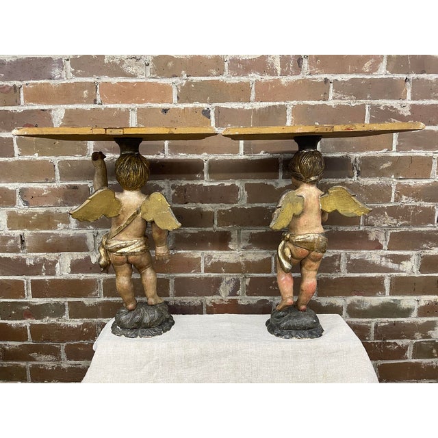 Two wonderfully carved wood Baroque style cherub side tables with a painted polychromed and partial gesso finish. Each...