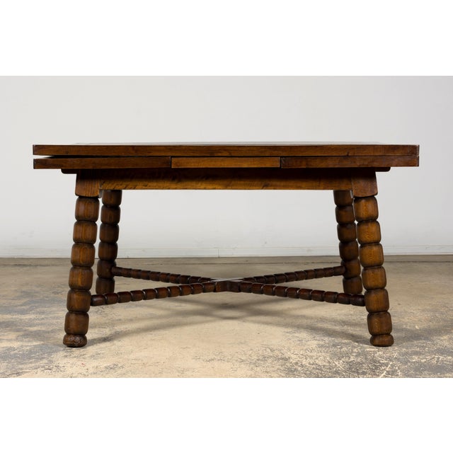 A late 19th century English Jacobean style extendable dining table crafted from walnut, circa 1880–1900. The table...