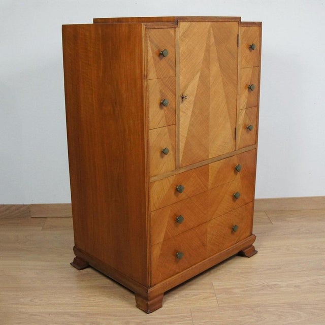 An Art Deco Tallboy Cabinet with satinwood cross banded veneer and walnut banding. Upper cabinet door opening to reveal a...