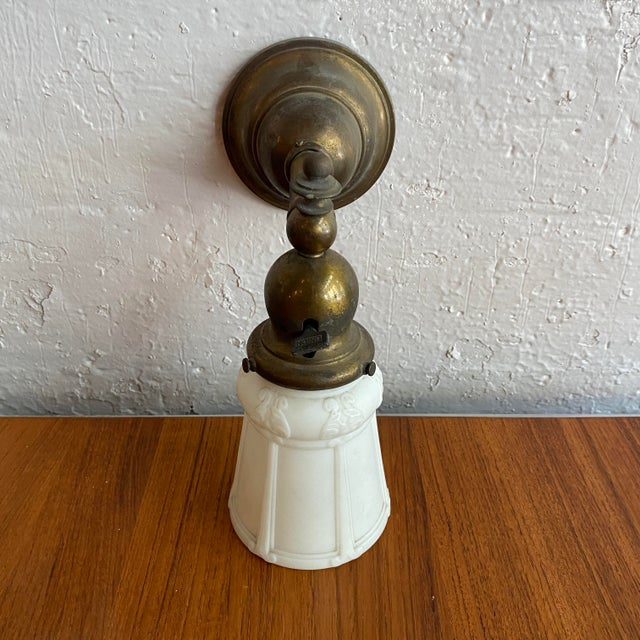 This early 20th-century industrial wall sconce features a brass pipe arm paired with an elegant frosted pressed glass...