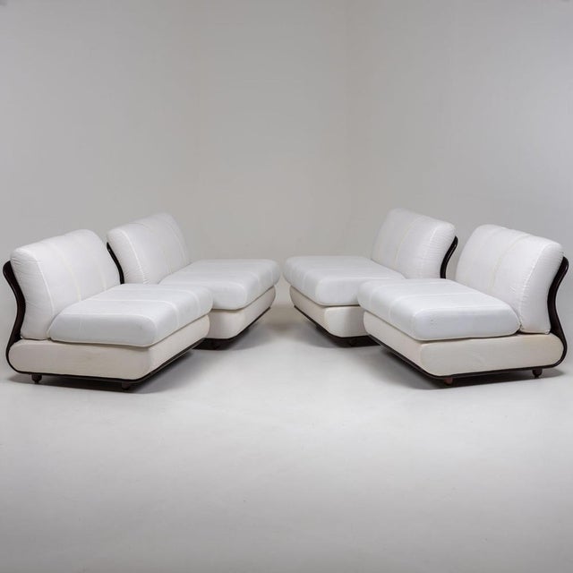 Set of four lounge chairs with curved backrests and tapered feet. The seats are heavily upholstered and covered with a...