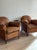 A pair of French club chairs from the 1920s with rounded backs, rolled arms, and deep seats that invite you to sink in....