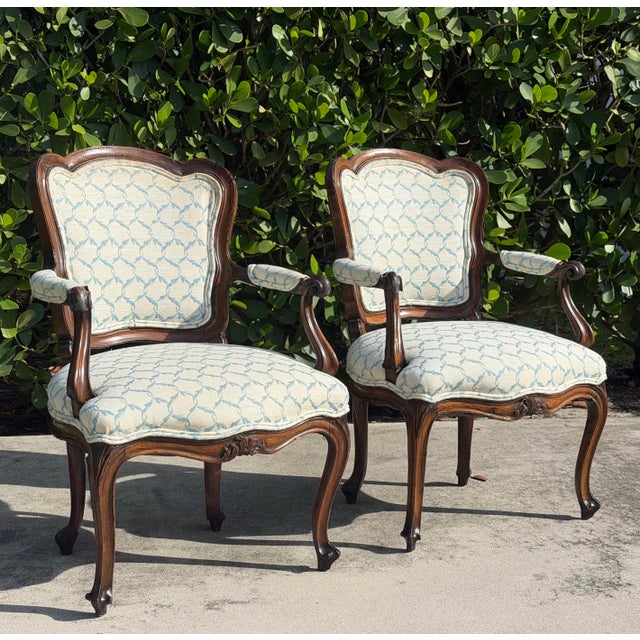 A handsome pair of antique Louis XV style bergère armchairs crafted in richly figured walnut with elegant cabriole legs,...