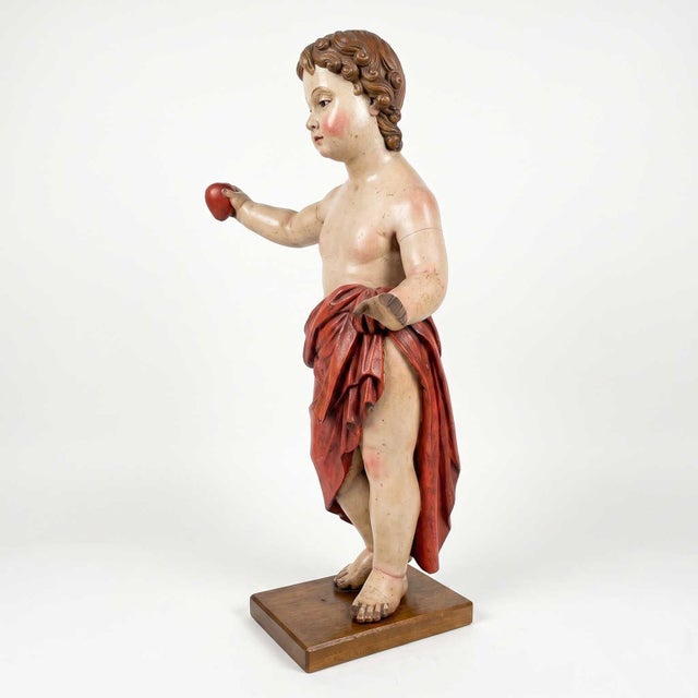 A 17th-century Italian devotional sculpture depicting Baby Jesus with a Heart, carved in wood and lacquered in polychrome....
