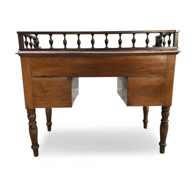 Antique walnut centerpiece desk from the mid-1800s in good condition. It features a large rectangular top bordered by a...