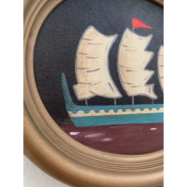 This petite seascape features a soft blue vessel set against a deep brown-black sky, with off-white sails and claret-toned...
