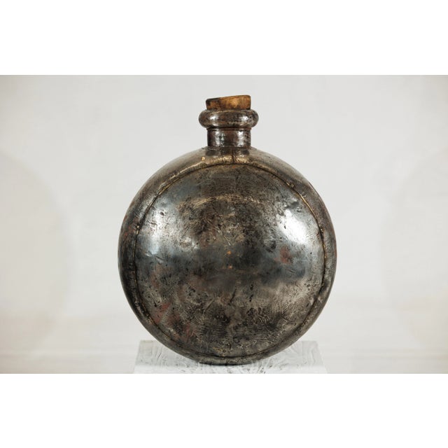 This vintage Indian water vessel presents a distinctive circular body with a short neck and wooden cork stopper, a form...
