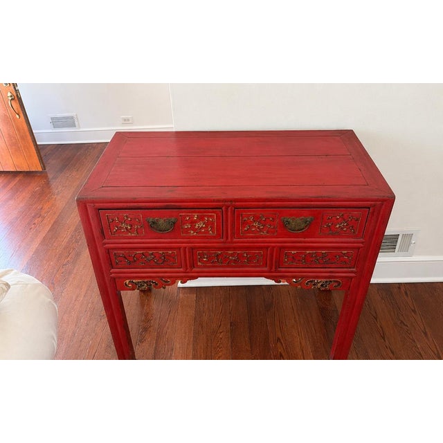 Striking vintage Chinese console table in a rich red lacquer finish with hand-painted gold detailing. Features two drawers...