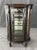 This elegant early 1900s curio cabinet features a graceful bowed front with glass-paneled sides and door, offering a...