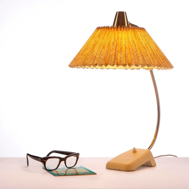 Original mid-century table lamp from the 1950s in a special design. This table or desk lamp has a lampshade in the pleated...