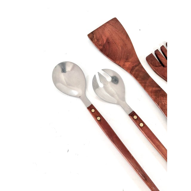Mid century modern salad server set featuring warm teak wood handles paired with stainless steel serving ends for a clean...