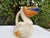 Decorative ceramic pelican pitcher by Animals & Co., featuring a colorful hand-painted coastal design with a fish-form...