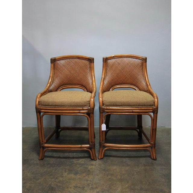 Vintage 1970's counter-height dining stools. Made of lacquered bamboo and woven rattan. Seat cushions recently...