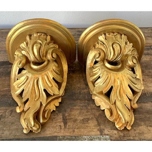 Elevate your walls with this stunning pair of vintage Rococo-style wall brackets, a masterful example of Hollywood Regency...