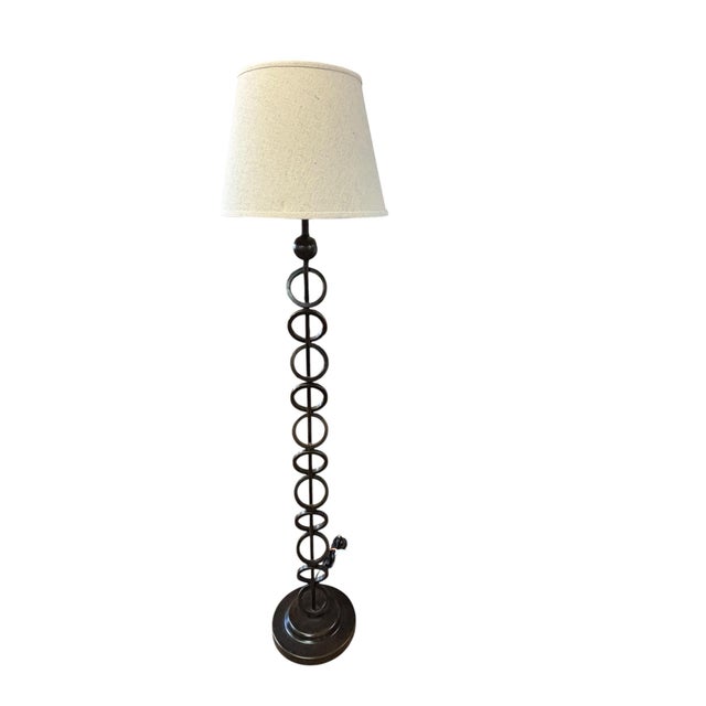 Elegant in its simplicity, this forged iron floor lamp showcases a distinctive off-center ring motif that lends an...