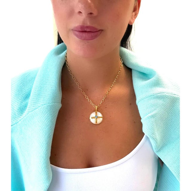 Beautiful Mother of Pearl accented with Brazilian blue topaz and paired with a gold filled chain. 18” Pendant has an...