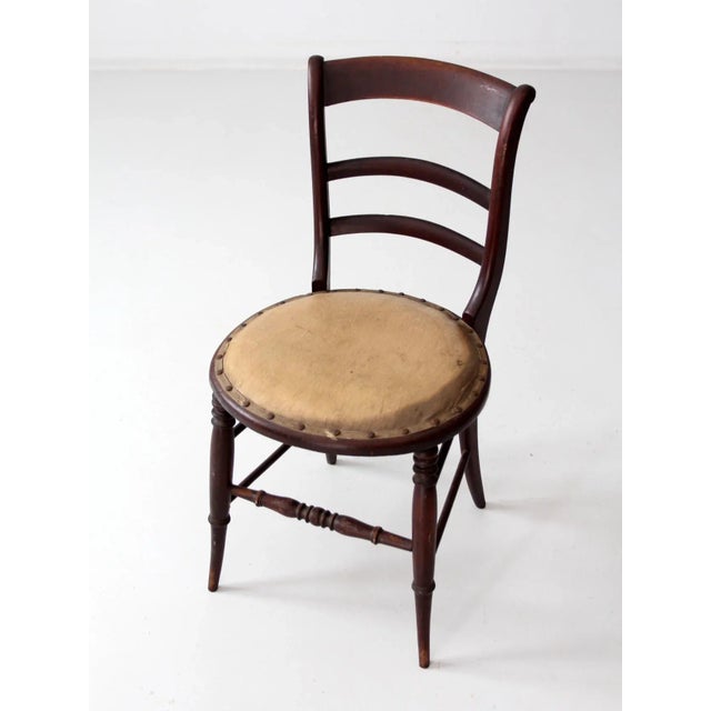 An elegant 19th century wooden chair crafted in dark-stained wood. The chair features finely turned legs, a classic ladder...