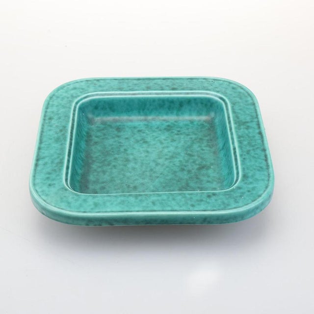 A beautiful stoneware dish by Wilhelm Kåge, produced in Sweden during the 1960s. The piece features a softly rounded...