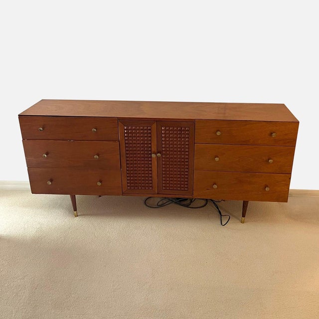 This dresser features a classic mid-century modern style with a warm wood finish. It has six spacious drawers and a center...