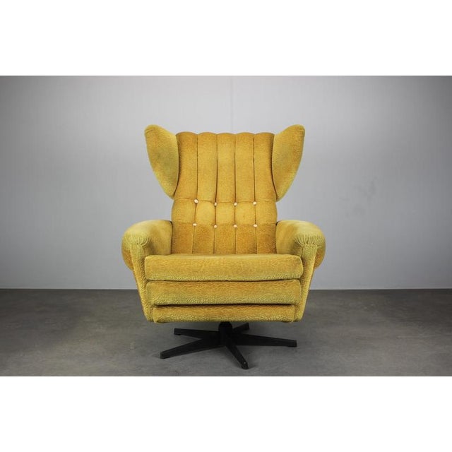 A mid-century swivel lounge chair manufactured in Czechoslovakia in the 1960s. This wingback armchair features a high...
