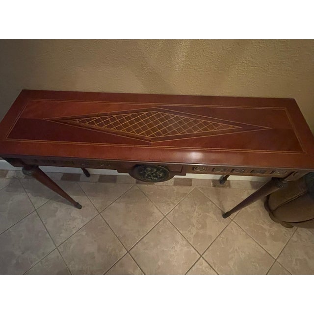 Elegant Luigi XVI and stately wooden console table featuring beautiful neoclassical details and an exquiite inlaid top....