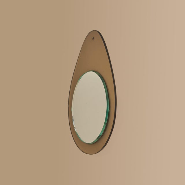 A 1960s Italian wall mirror defined by its sculptural teardrop silhouette and smoked acrylic surround. The translucent...