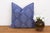 A repeating diamond medallion in pale ink covers the full face of this pillow, hand block-printed on deep indigo-blue...