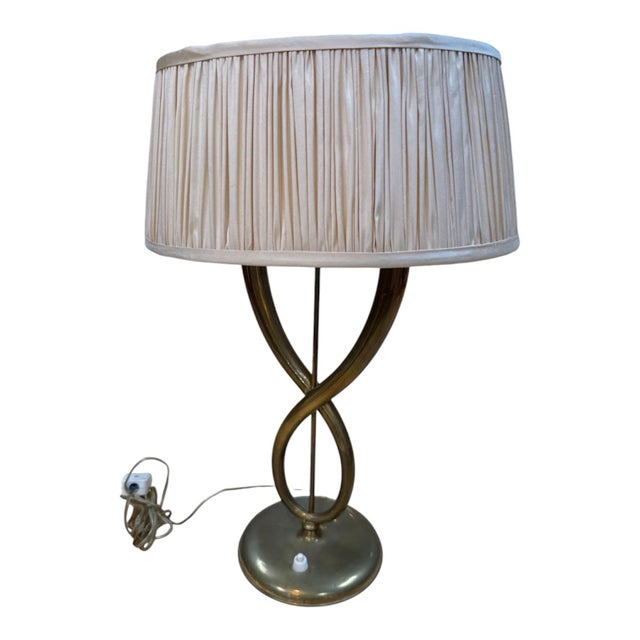 Elegant Italian table lamp from the 1950s, defined by its sculptural brass base composed of two curved arms that...